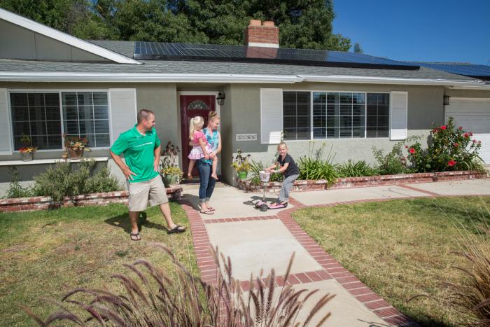 A family is standing outside of their home with solar installed by Sea Bright.