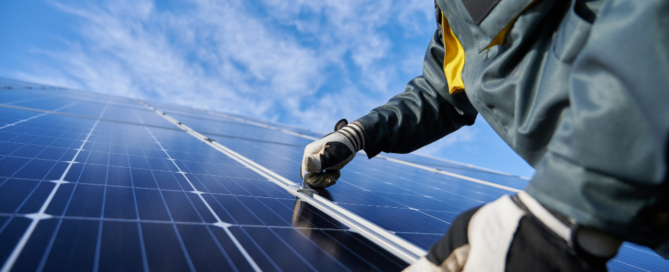 Technician installing solar panels under a clear blue sky