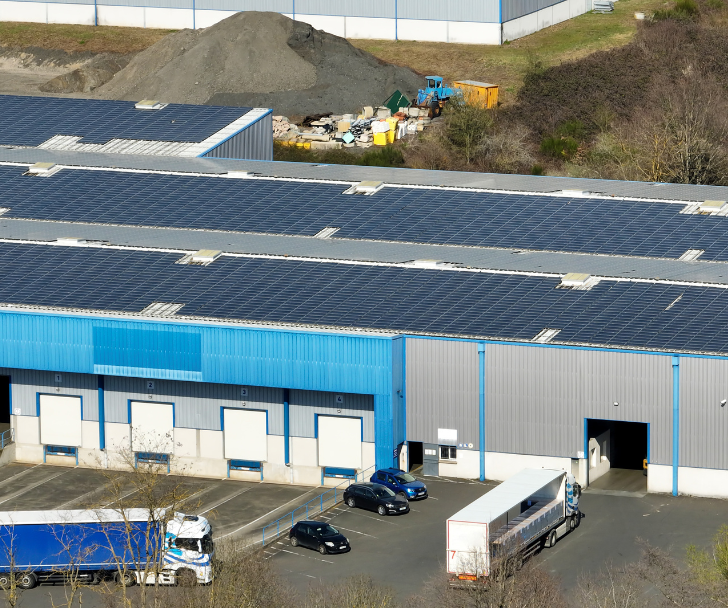 a building with solar panels that have cars parked in front of it a building with solar panels that have cars parked in front of it